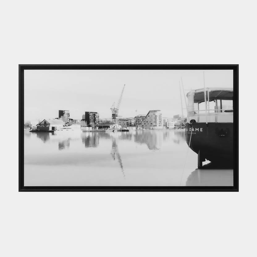 La Dame, oeuvre encadrée : Photographie fine art en noir et blanc d'un paysage urbain industriel au bassin à flot de Bordeaux avec l'apparition de la péniche La Dame anciennement la dame de Shangaiï. Image capturée en janvier 2021 par Anne-Laure Boisseau.