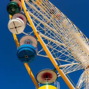 « Soleil Forain 1 », photographie d’art en couleur. Grande roue multicolore sur fond de ciel bleu, vue en contre-plongée. Elle rayonne telle un soleil dans une diagonale dynamique, captée à Bordeaux lors de la Foire aux Plaisirs en octobre 2021.