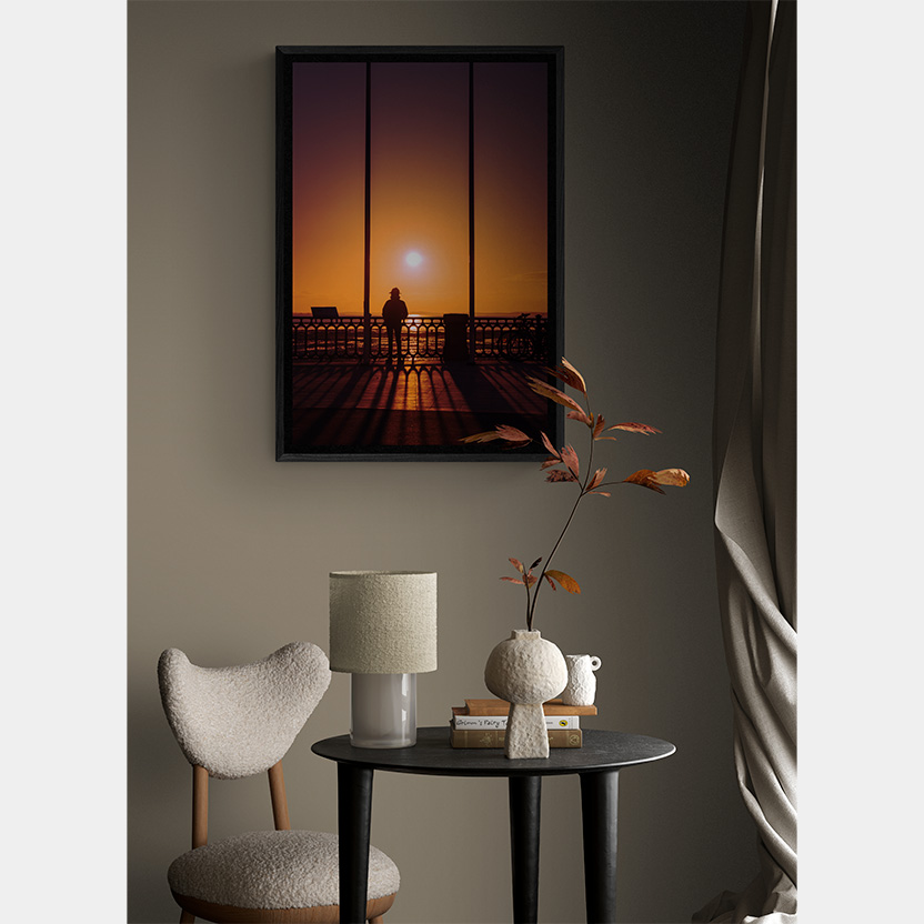 Image in situ de Fenetre sur bassin, une des photographies d'art proposée par l'artiste Anne-Laure Boisseau. Dans un coin cosy couleur taupe, l'oeuvre dévoile des couleurs orangées voluptueuses qui nous projette tendrement au bord du Bassin d'Arcachon, à la jetée d'Andernos-les-Bains.