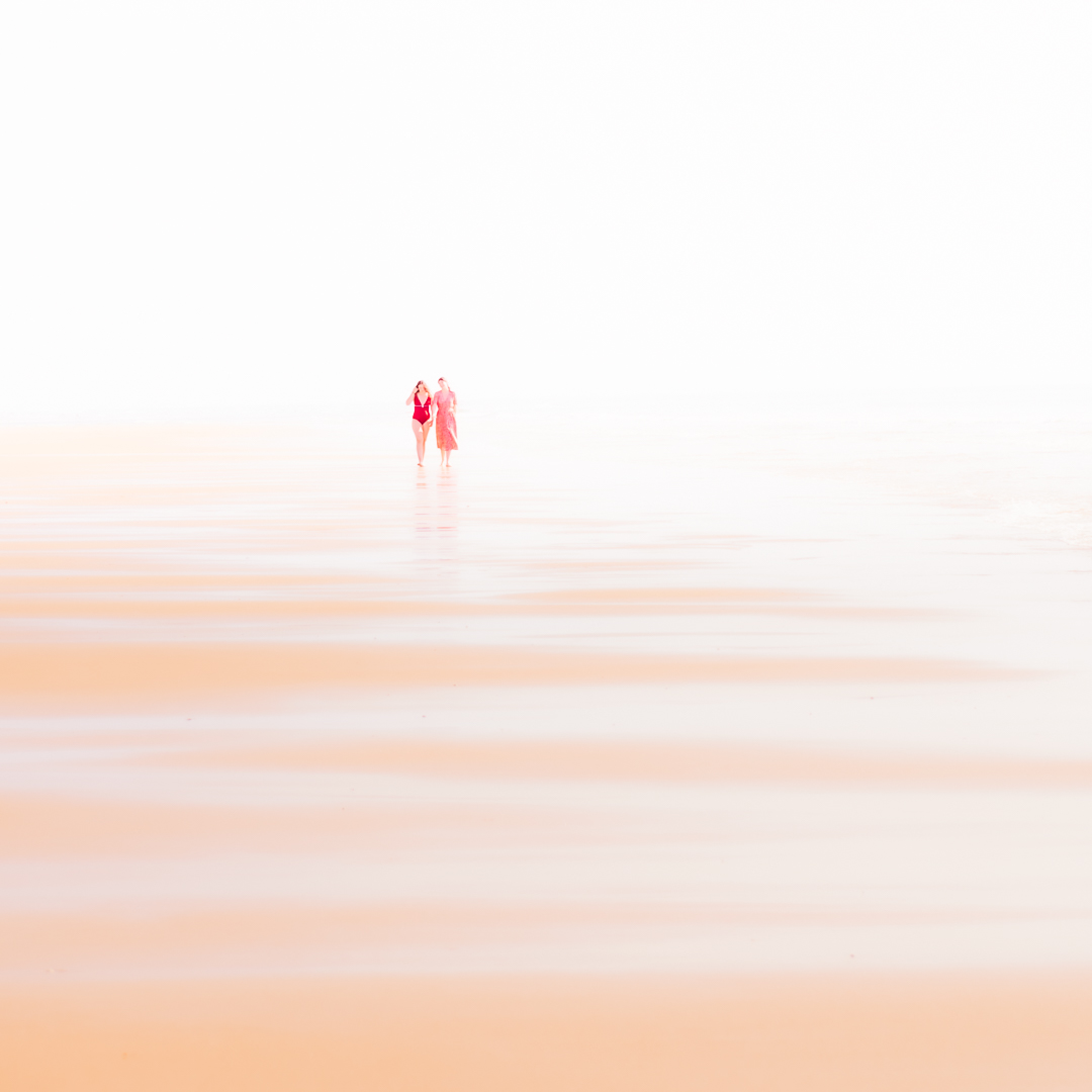 Comme une délicate aquarelle, cette image capture un moment de complicité et d’intimité entre deux adolescentes marchant sur le chemin de l'amitié, représenté par l’ondulation des vagues qui caressent le sable.